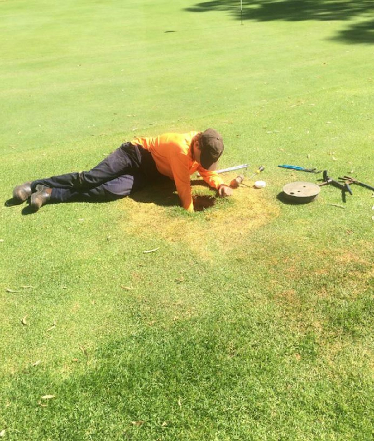 Charles Harding lying on a field in PPE, working in a hole.